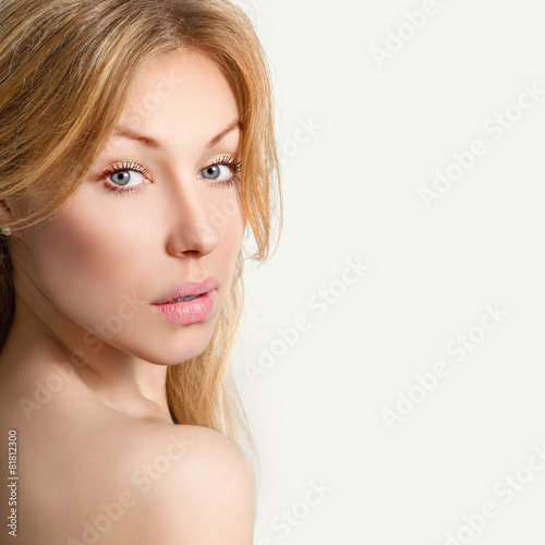 Портрет красивой молодой светловолосой женщины на сером фоне.
