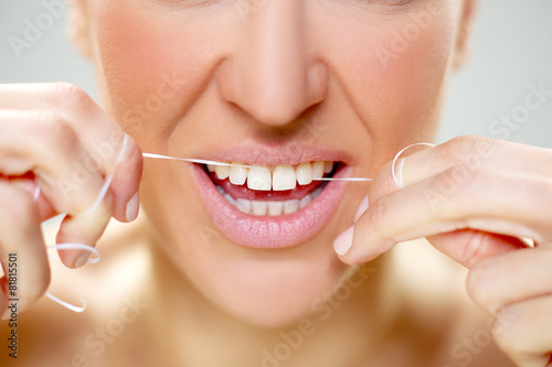 woman cleaning tooth with floss