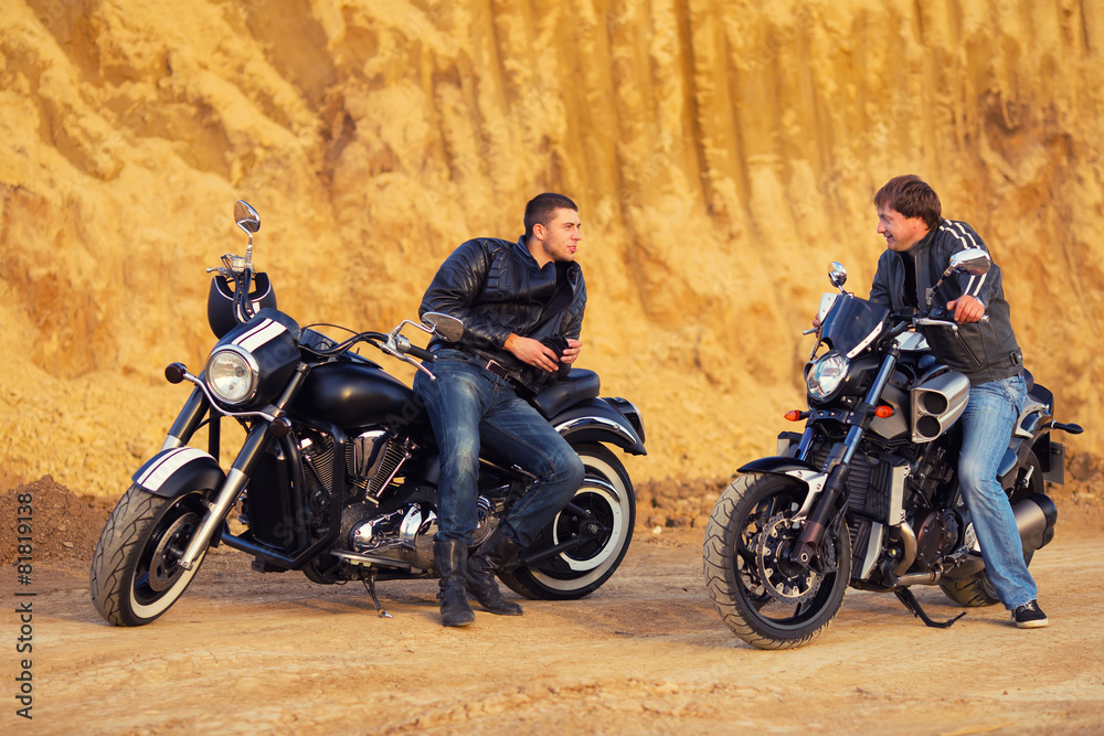 Fototapeta premium Two bikers on unknown motocycles talking on desert road