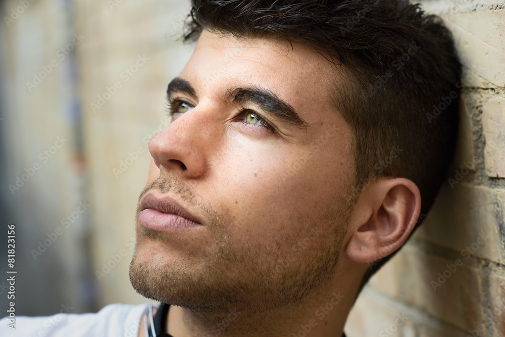 Handsome young man with blue eyes posing near a wall Handsome young man with blue eyes posing near a wall
