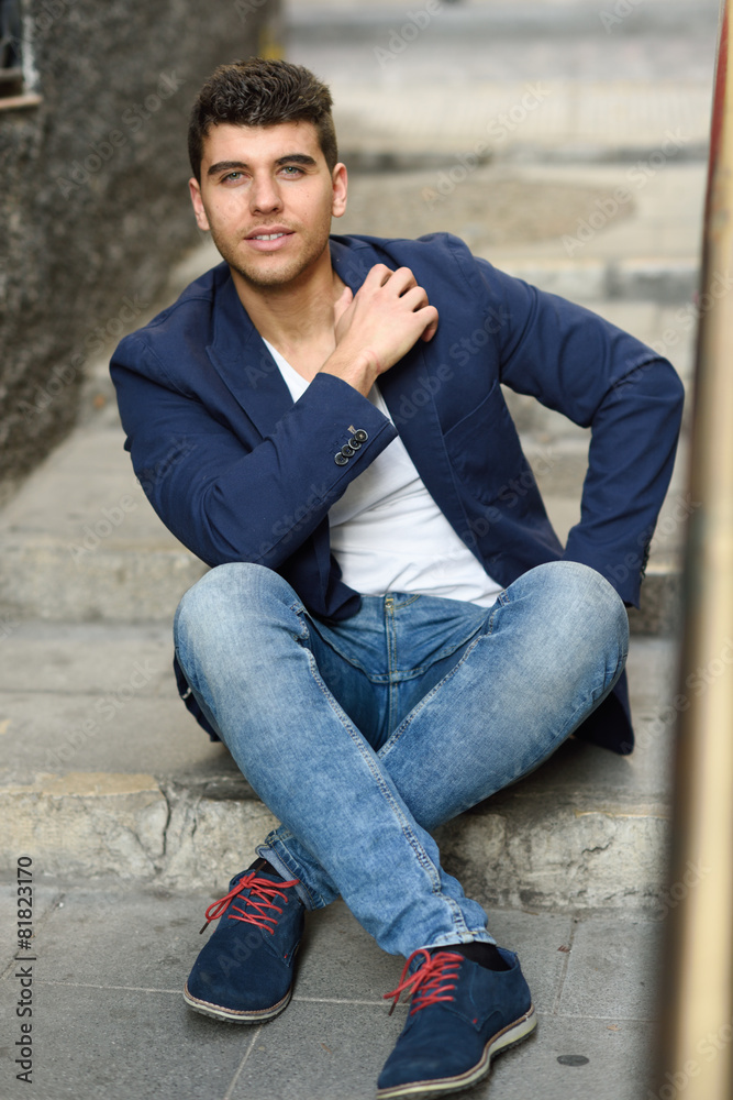 Handsome young man with blue eyes posing near a wall Handsome young man with blue eyes posing near a wall