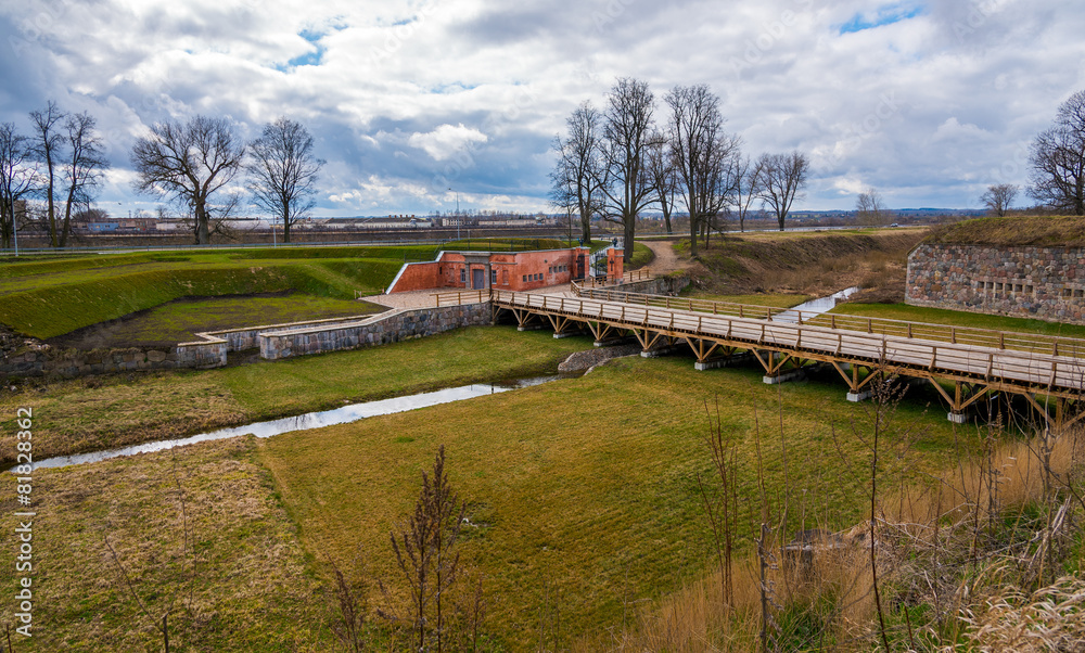 View on wooden bridge over river and gates of fortress