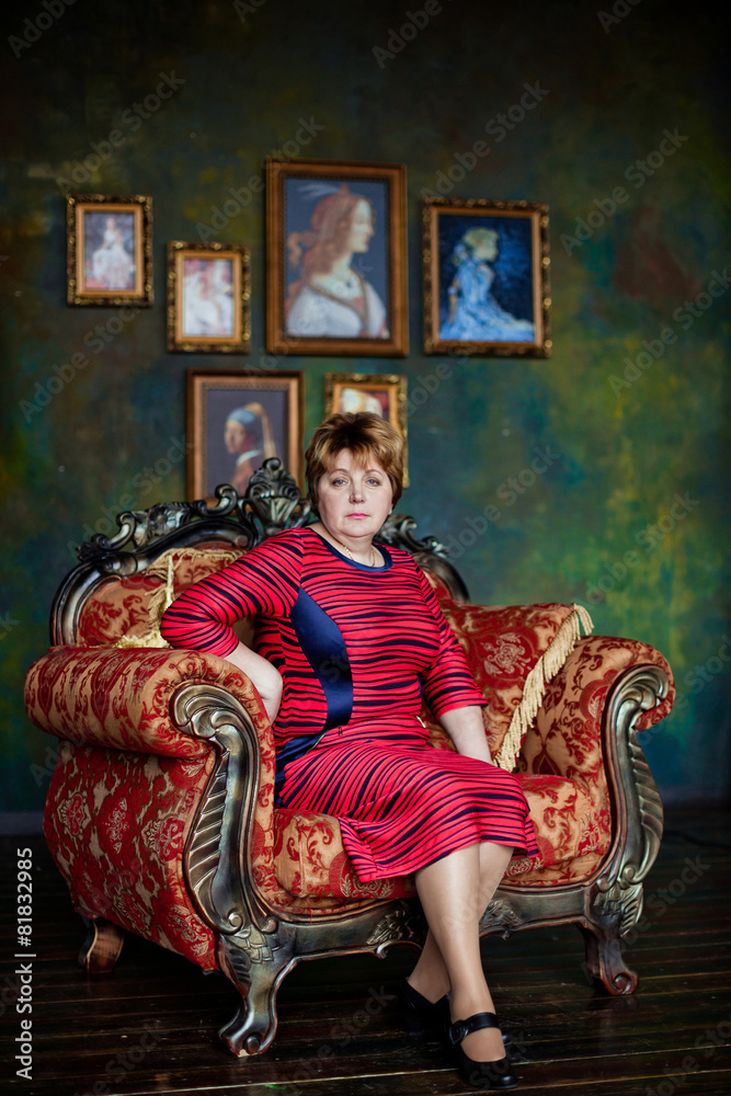 Portrait of mid-adult woman looking at camera sitting in armchair in bright living room