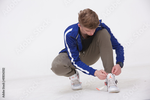 young guy in sportswear tying shoelaces on sneakers