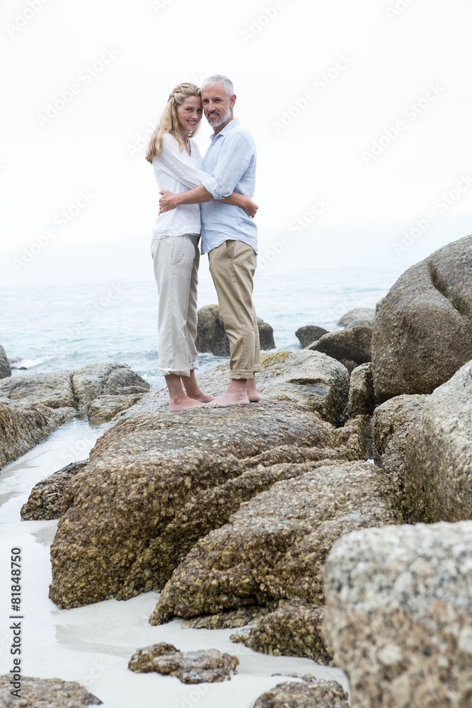 Happy couple standing on the rock and looking at camera