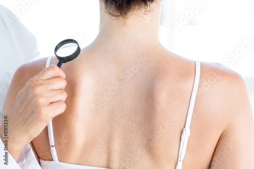 Doctor examining patient with magnifying glass