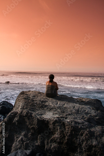 Frau auf Felsen schaut auf Horizont Abendrot