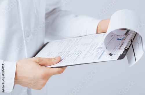 male doctor holding prescription paper in hand