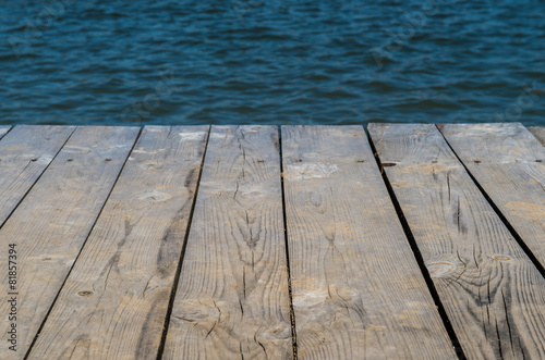 Wooden deck by water, background with copy space