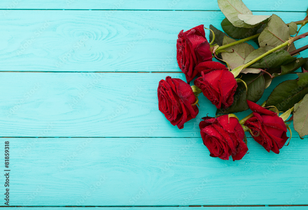 Red roses on blue wooden background. Top view