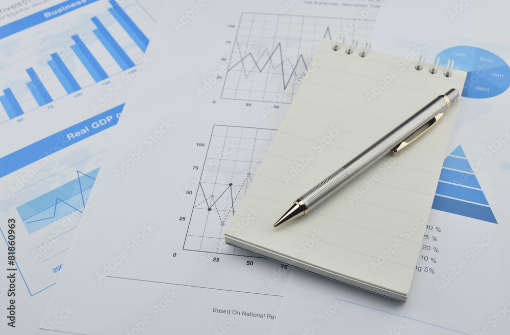 Pen and notebook on financial chart and graph Pen and notebook on financial chart and graph