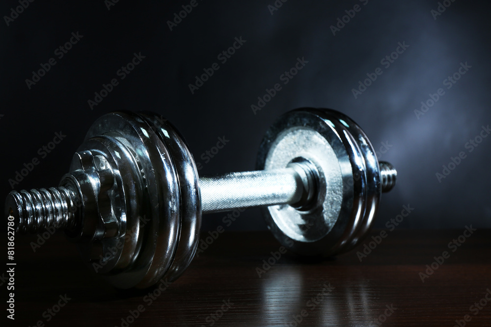 Dumbbells on wooden floor, on dark background Dumbbells on wooden floor, on dark background
