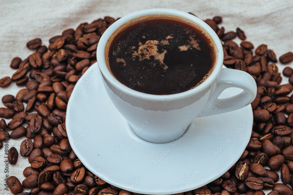 Cup of coffee and roasted beans on beige background