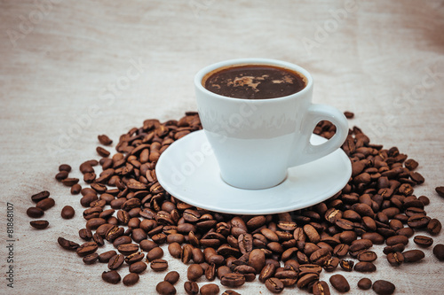 Cup of coffee and roasted beans on beige background