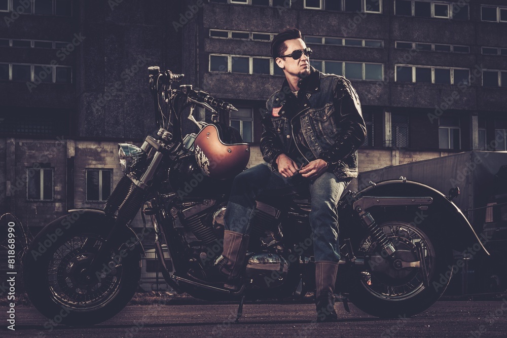 Biker and his bobber style motorcycle on a city streets Biker and his bobber style motorcycle on a city streets