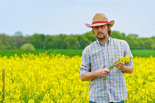 Farmer Standing in Oilseed Rapeseed Agricultural Field photo