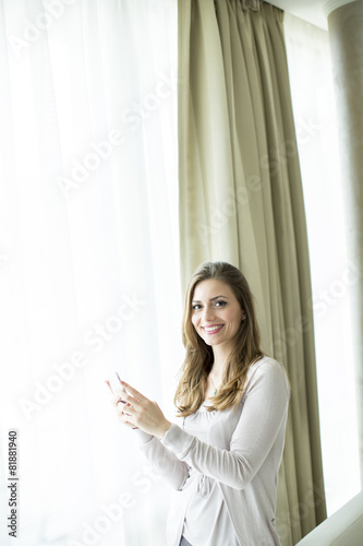 Young woman with mobile phone by the window © BGStock72