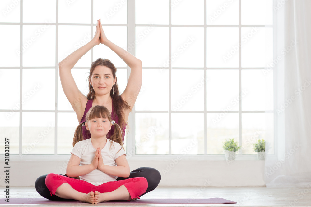Young mother and daughter sitting in lotus position Young mother and daughter sitting in lotus position