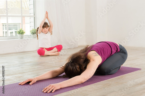 Young mother and daughter doing yoga exercise