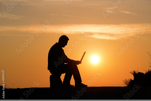 Silhouette of businessman working with laptop