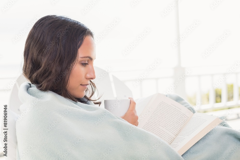 Pretty brunette sitting on a chair and reading a book Pretty brunette sitting on a chair and reading a book
