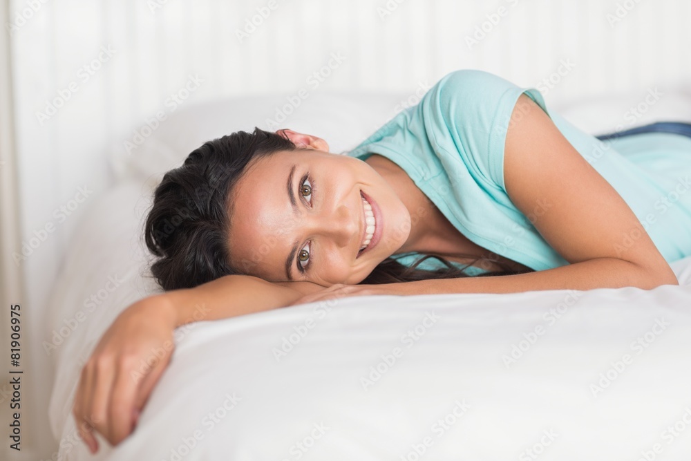 Happy brunette lying on bed - obrazy, fototapety, plakaty 