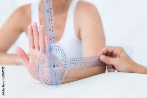 Doctor measuring wrist with goniometer photo