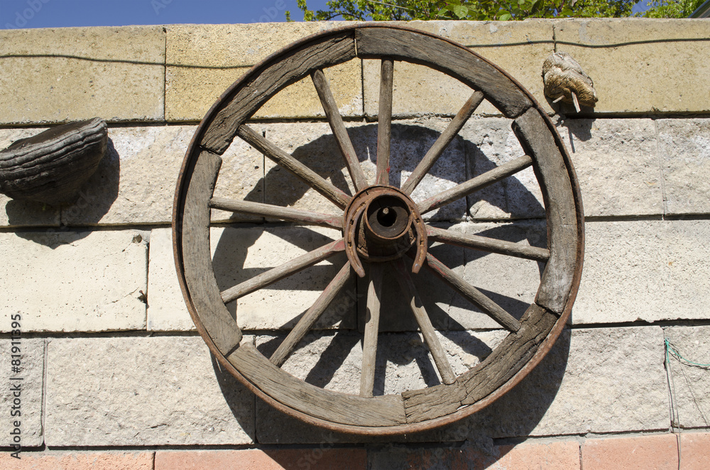 Old wooden wheel hanging on the stone wall