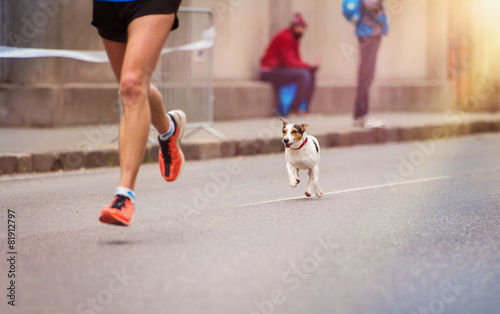 Unrecognizable young runner and a dog at the city race photo