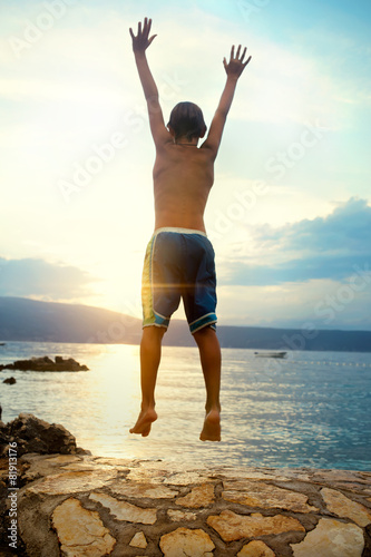 Fototapeta Naklejka Na Ścianę i Meble -  boy jumping and taking a deep breath at the sunset