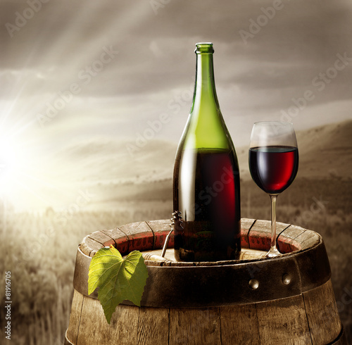 Fototapeta Naklejka Na Ścianę i Meble -  Still-life with glass of wine and bottle on the barrel in the vi