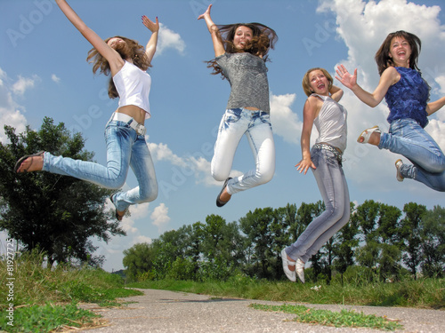 happy group of female students jumping in the village