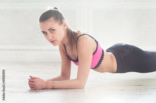 Slim fitnes young girl with ponytail doing planking exercise