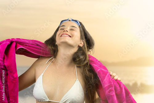 relaxed girl in beachwear with swimming goggles against beach a