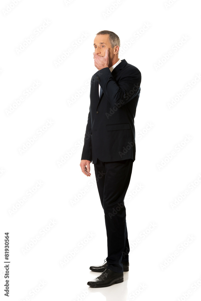 Full length businessman covering mouth Full length businessman covering mouth