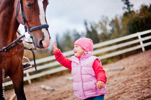 Child with horse in paddok photo