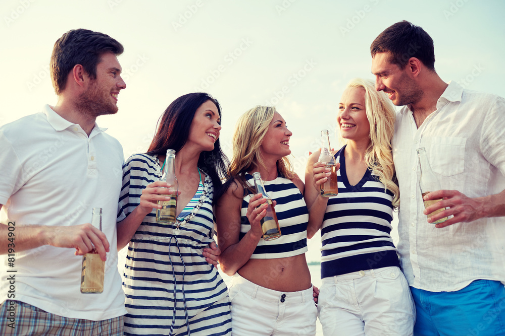 smiling friends with drinks in bottles on beach smiling friends with drinks in bottles on beach