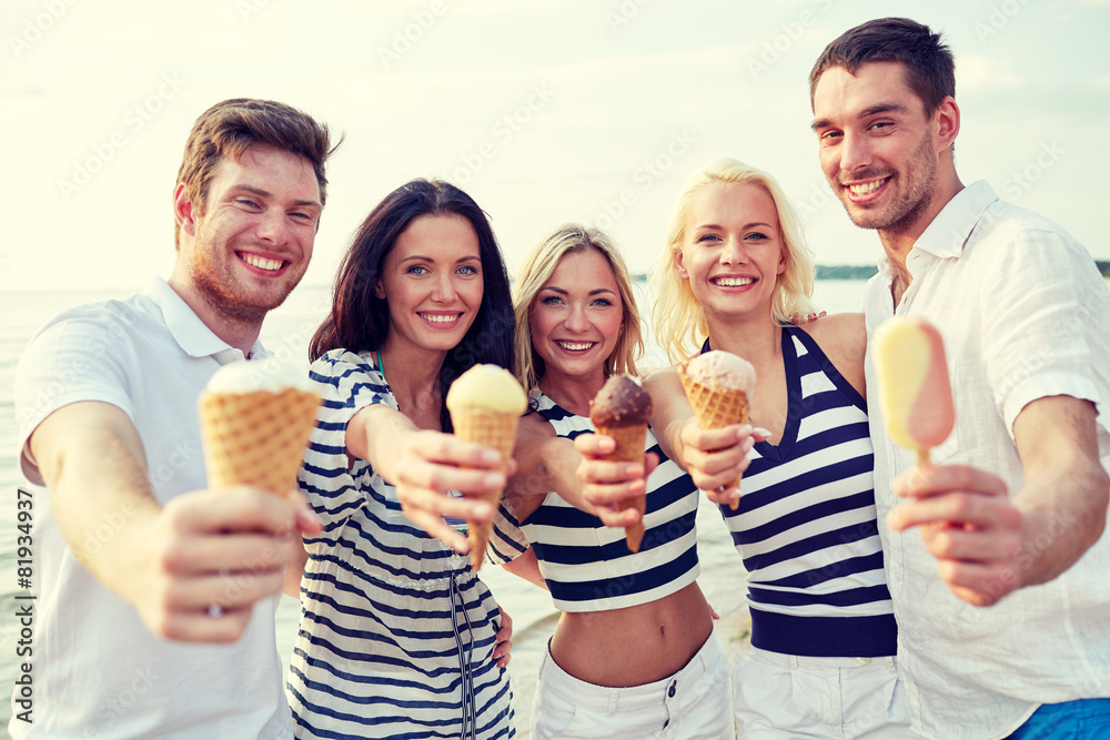 Obraz premium smiling friends eating ice cream on beach