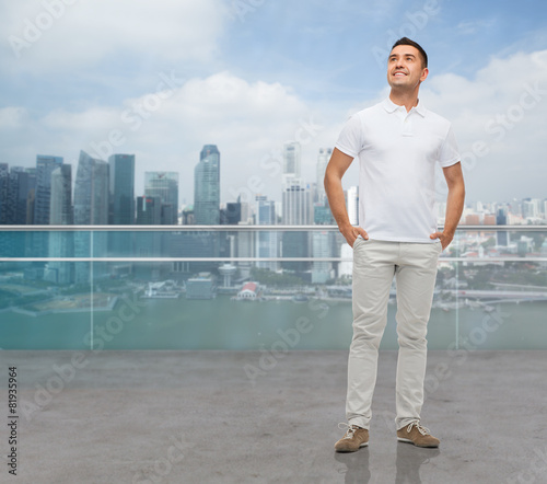 smiling man with hands in pockets looking up