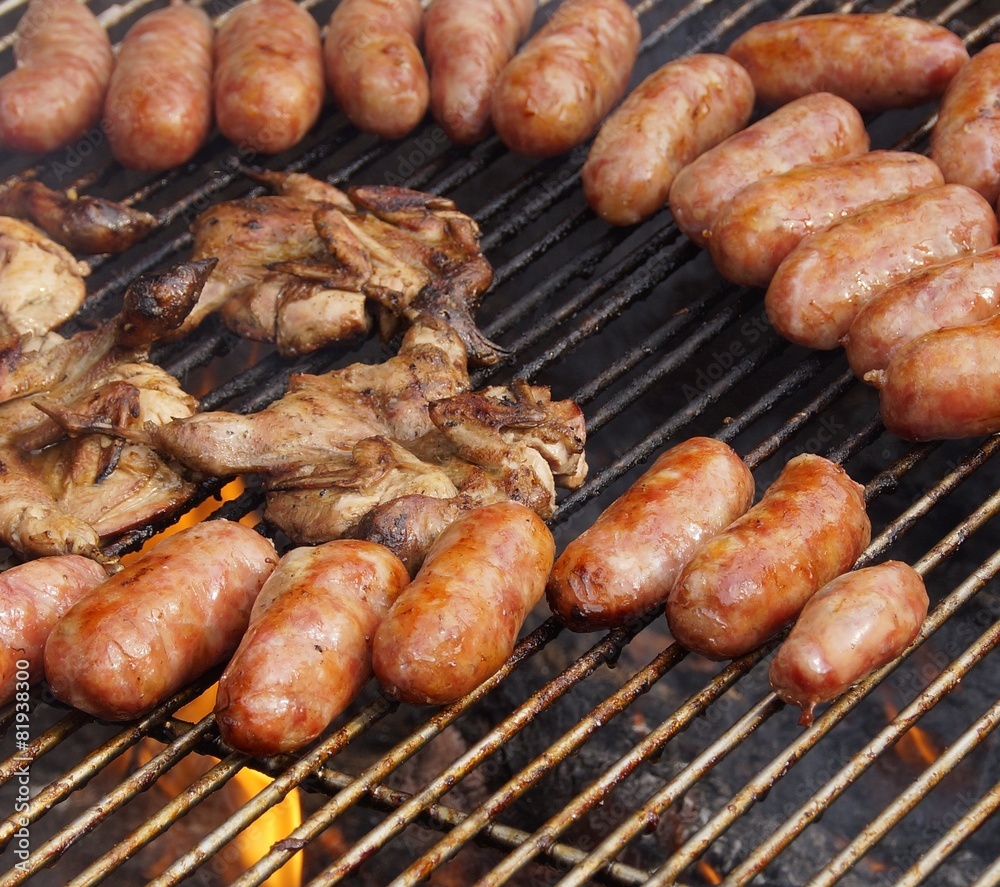 Barbecued meat and pork sausages on grill