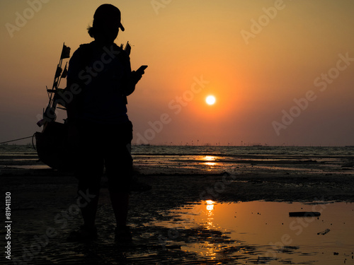 Silhouette of a girl and fishing boat in sunset on the beach