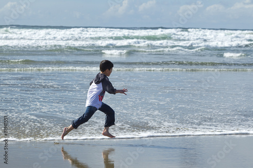 Boy runs on beach in Newport, Oregon.