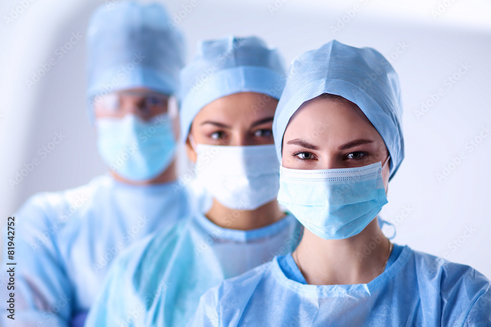 Surgeons team, wearing protective uniforms,caps and masks Surgeons team, wearing protective uniforms,caps and masks