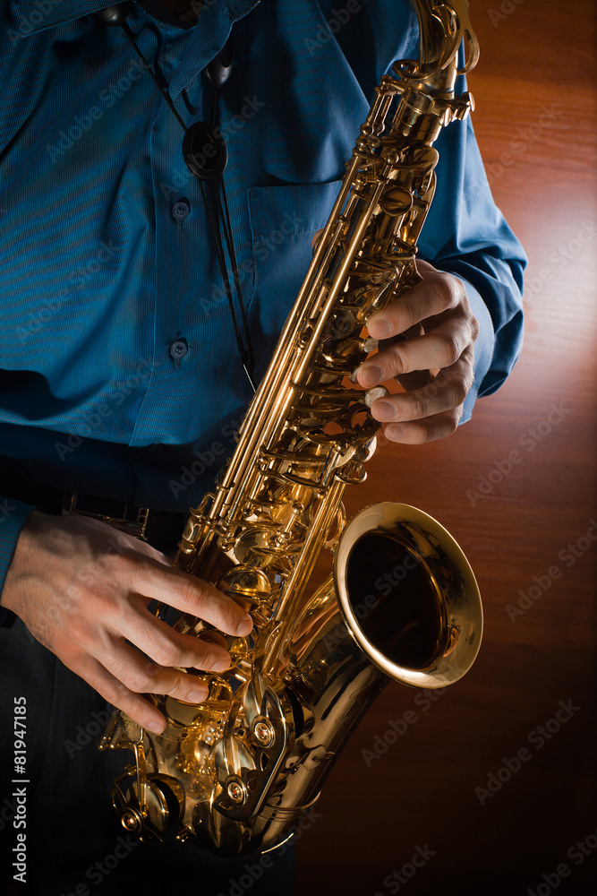 Obraz premium Man playing jazz saxophone closeup. Golden sax.