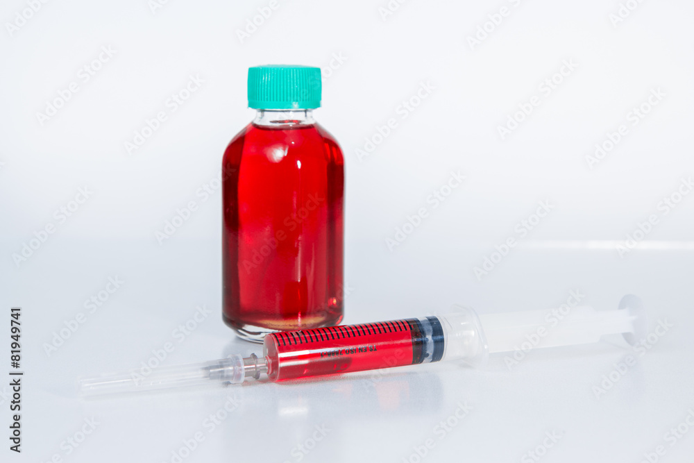 Red liquid in disposable syringe with bottle of red content