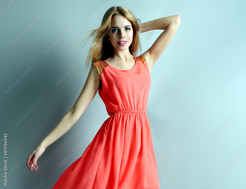 Beautiful young woman in dress posing on blue background