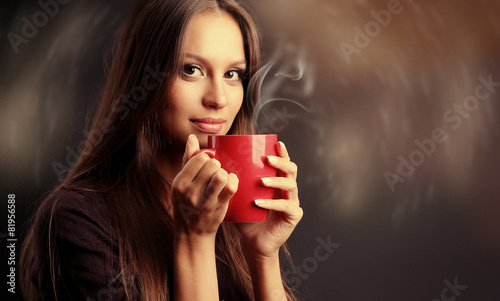 Beautiful young woman with cup of coffee on dark background