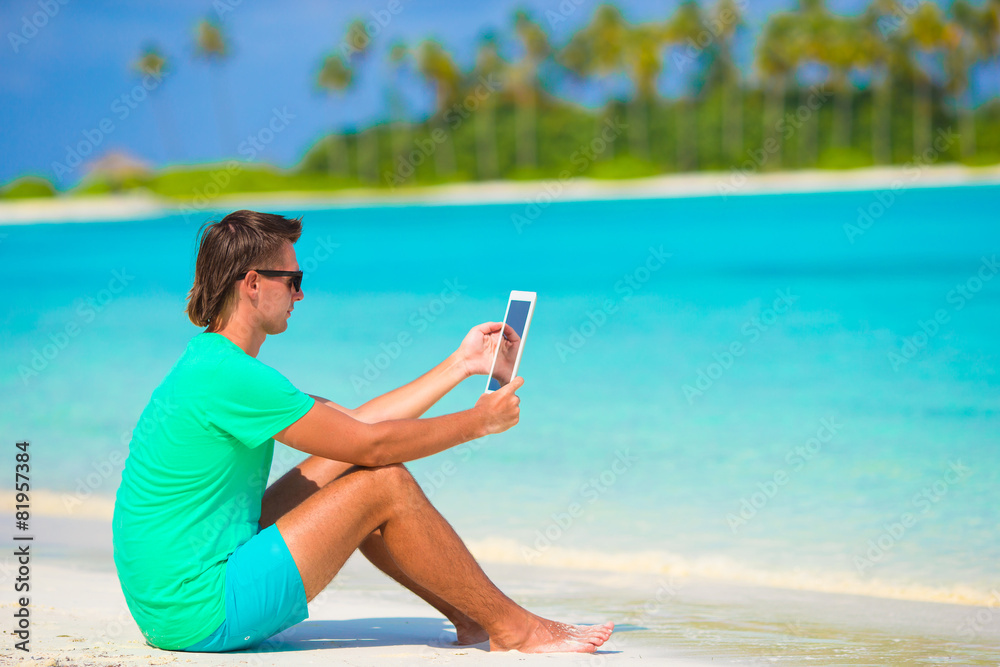Young man with laptop at tropical beach