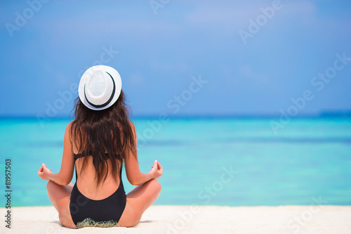 Healthy young woman sitting in yoga position meditating on the © travnikovstudio