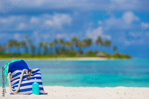 Stripe bag, blue towel, sunglasses, sunscreen bottle and